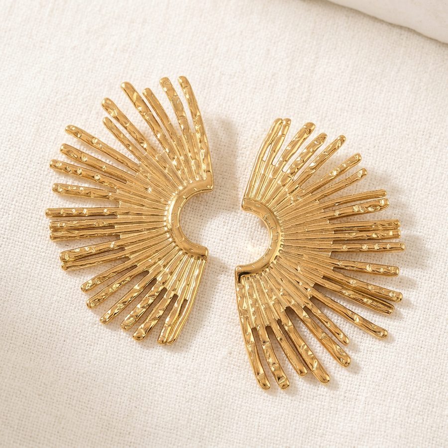 Gold sunburst fan earrings flat lay on linen