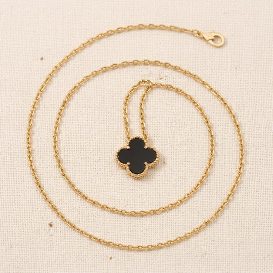 Black clover necklace arranged on warm linen