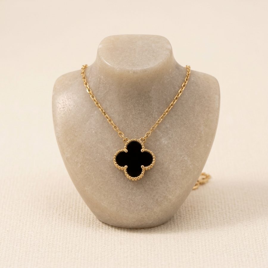 Black clover pendant necklace displayed on a stone stand